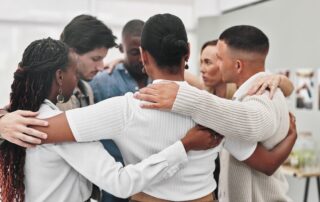 Group therapy, counseling and people hug in rehabilitation center for support, empathy or solidarity. Help, psychology and friends with safety prayer circle for trauma healing, gratitude or thank you