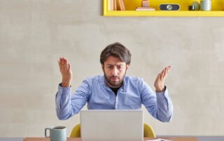 An upset man during a video call in front of a laptop.